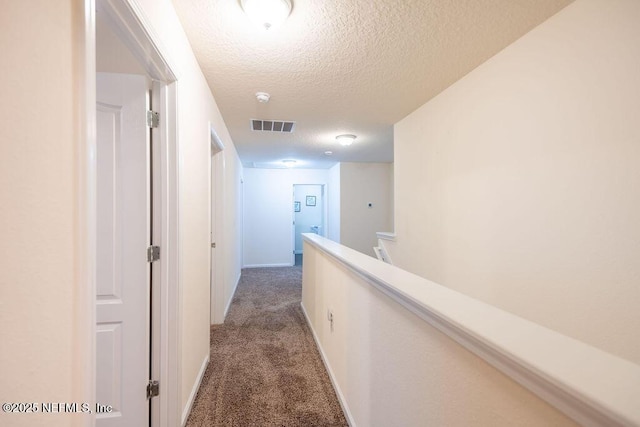 hallway with carpet and a textured ceiling