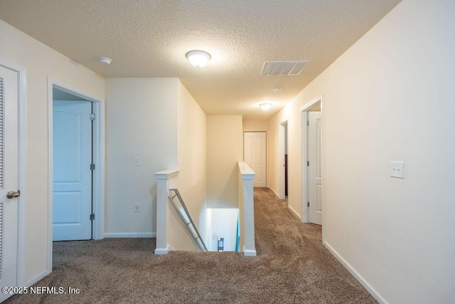 corridor featuring dark carpet and a textured ceiling