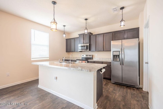 kitchen with dark wood-type flooring, hanging light fixtures, stainless steel appliances, dark brown cabinetry, and a center island with sink