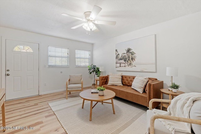 living room featuring ceiling fan, a textured ceiling, and light wood-type flooring