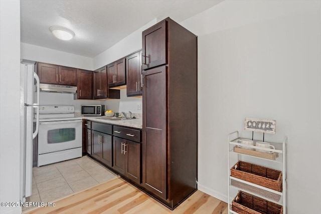 kitchen featuring dark brown cabinetry, sink, white appliances, and light wood-type flooring