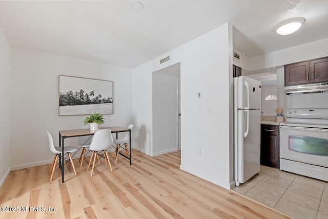 kitchen with white appliances, dark brown cabinets, and light wood-type flooring