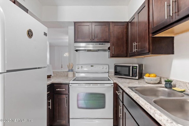 kitchen featuring white appliances, dark brown cabinetry, and sink