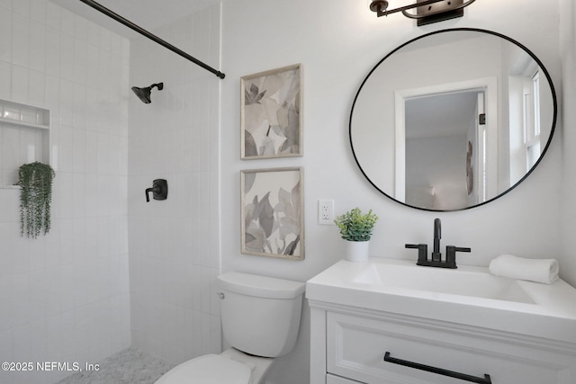 bathroom with vanity, toilet, and tiled shower