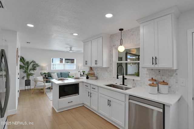 kitchen featuring decorative light fixtures, tasteful backsplash, white cabinetry, dishwasher, and sink