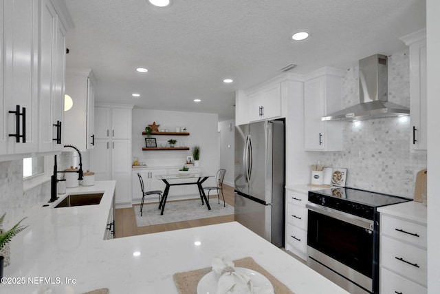 kitchen featuring sink, stainless steel appliances, white cabinets, and wall chimney exhaust hood