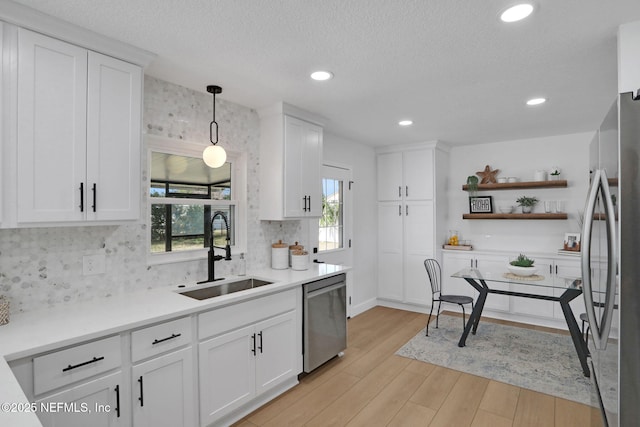 kitchen featuring white cabinetry, appliances with stainless steel finishes, sink, and decorative light fixtures