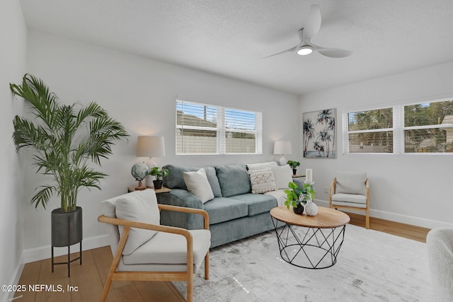 living room featuring ceiling fan, hardwood / wood-style floors, and a textured ceiling