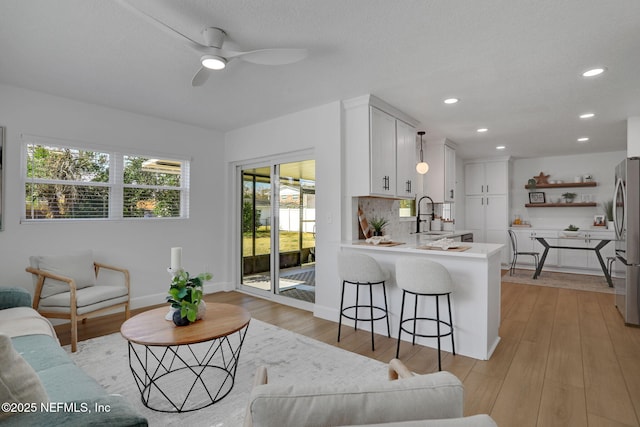 living room featuring sink, ceiling fan, and light wood-type flooring