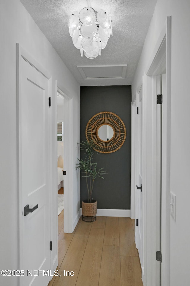 corridor featuring a textured ceiling and light wood-type flooring