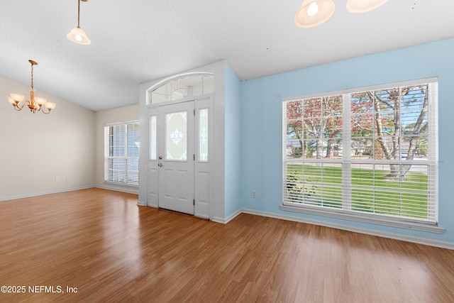 foyer featuring an inviting chandelier, vaulted ceiling, a textured ceiling, and light wood-type flooring