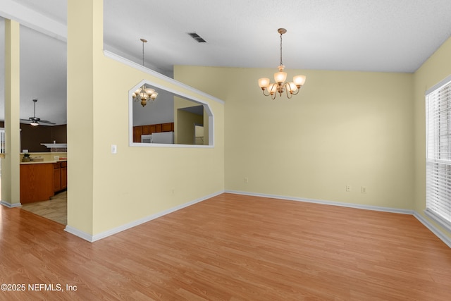 empty room with ceiling fan with notable chandelier and light hardwood / wood-style flooring