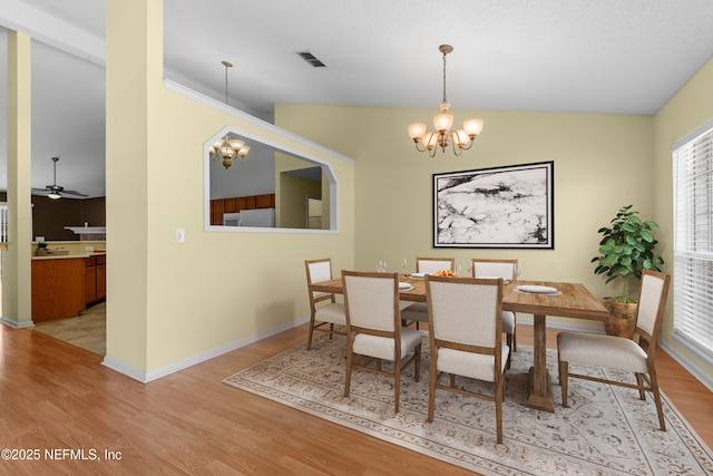 dining space featuring ceiling fan with notable chandelier, lofted ceiling, and light hardwood / wood-style floors