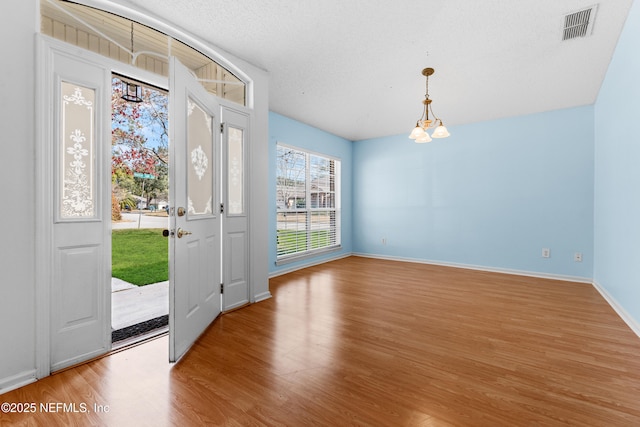 foyer entrance with a textured ceiling, light hardwood / wood-style flooring, and a chandelier