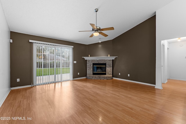 unfurnished living room with ceiling fan, a fireplace, high vaulted ceiling, and light wood-type flooring