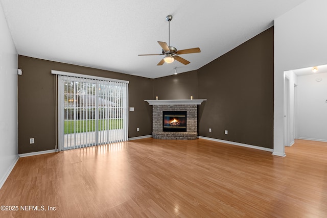 unfurnished living room with a brick fireplace, high vaulted ceiling, ceiling fan, and light hardwood / wood-style flooring