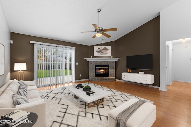 living room featuring ceiling fan, lofted ceiling, wood-type flooring, and a fireplace