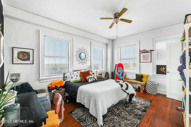 bedroom featuring ceiling fan, dark hardwood / wood-style flooring, and multiple windows