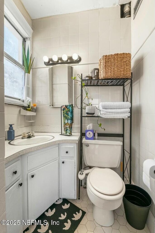 bathroom featuring tile walls, vanity, tile patterned floors, and toilet