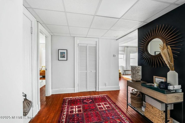 home office with dark wood-type flooring and a paneled ceiling