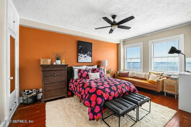 bedroom with dark wood-type flooring, ceiling fan, ornamental molding, and a textured ceiling