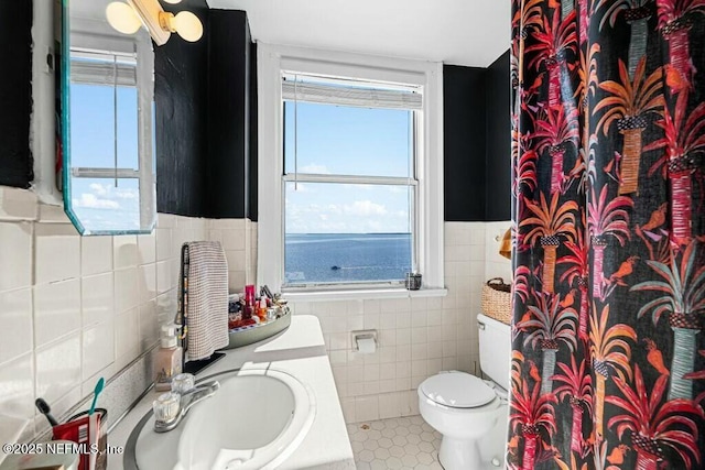 bathroom with vanity, a water view, plenty of natural light, and tile walls