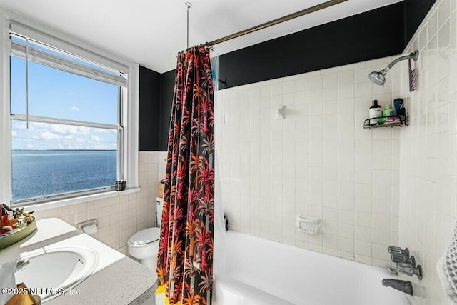 full bathroom with tile walls, shower / bath combination with curtain, toilet, and a water view