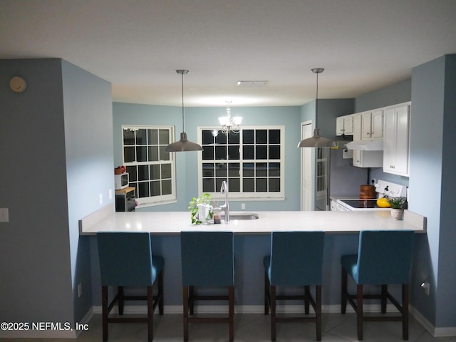 kitchen featuring white cabinetry, kitchen peninsula, range, sink, and pendant lighting