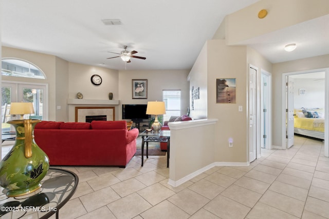 tiled living room with ceiling fan, a fireplace, and french doors