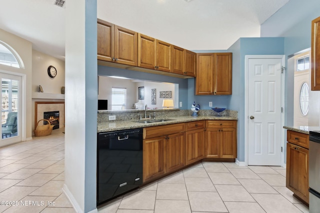 kitchen featuring dishwasher, light stone countertops, sink, and light tile patterned floors