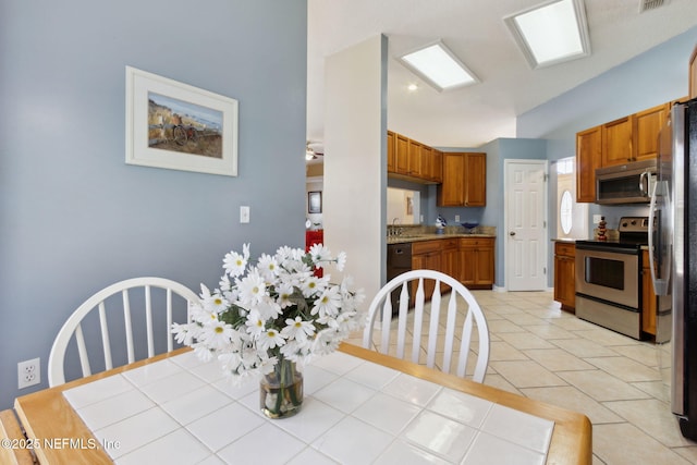 tiled dining area featuring vaulted ceiling and sink