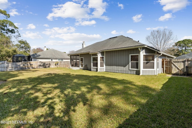 rear view of property featuring a yard and a sunroom