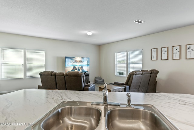 kitchen with light stone counters, sink, and a textured ceiling