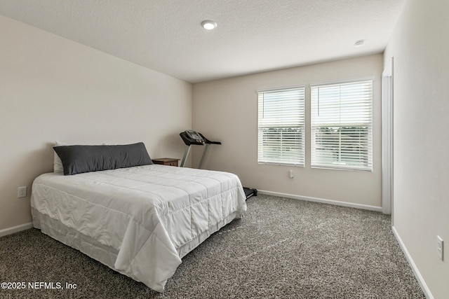 bedroom with a textured ceiling and dark colored carpet