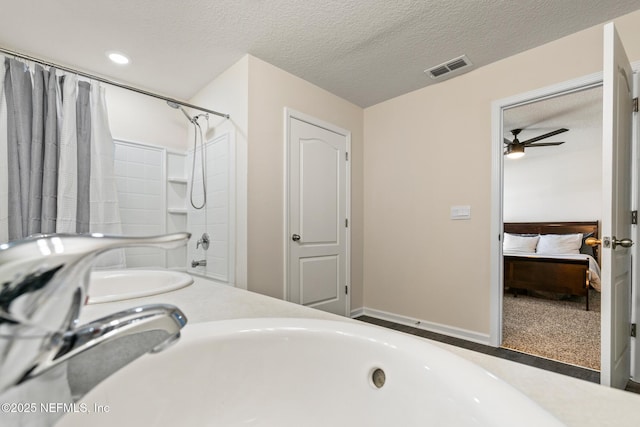 bathroom with ceiling fan, double sink, tub / shower combination, and a textured ceiling