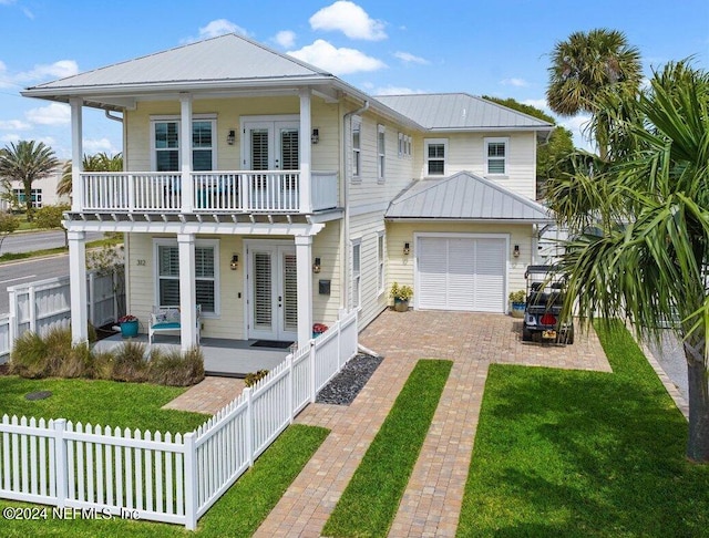 view of front of home with french doors, a garage, a balcony, a patio, and a front lawn