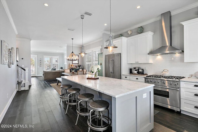 kitchen with tasteful backsplash, high end appliances, a center island, crown molding, and wall chimney range hood