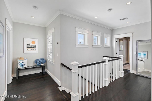 hall with ornamental molding, visible vents, hardwood / wood-style floors, and an upstairs landing