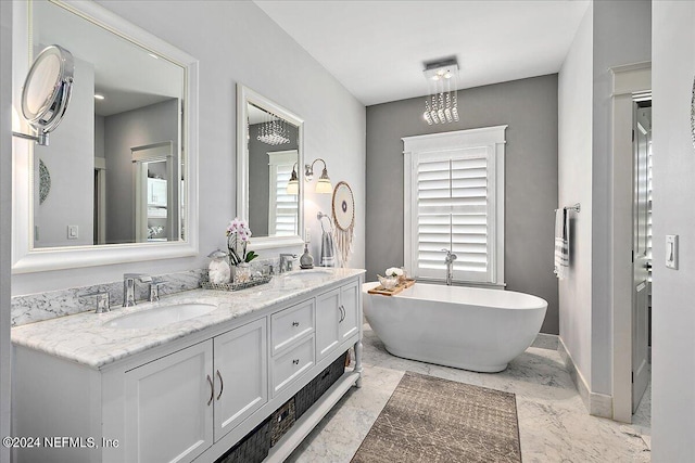 bathroom featuring marble finish floor, a sink, a freestanding bath, and double vanity