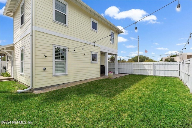 rear view of house featuring a patio, a lawn, and a fenced backyard