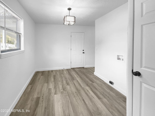 unfurnished dining area with light hardwood / wood-style floors and a textured ceiling