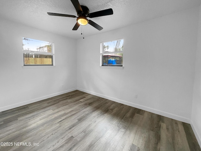 empty room with a wealth of natural light, hardwood / wood-style floors, and a textured ceiling