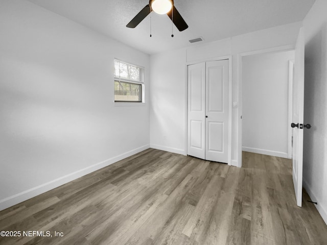 unfurnished bedroom featuring ceiling fan, a closet, and light hardwood / wood-style flooring