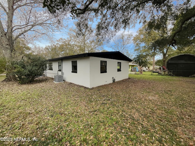 view of side of home with central AC and a lawn