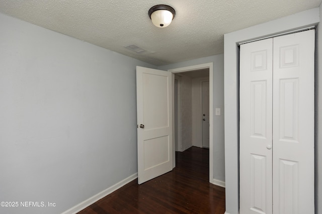 hallway with dark hardwood / wood-style floors and a textured ceiling