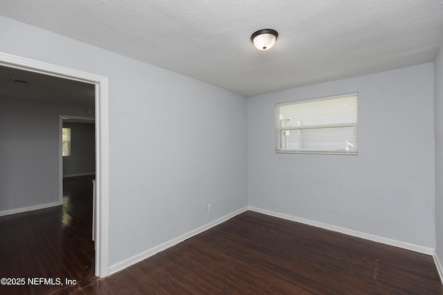 spare room featuring dark wood-type flooring and a textured ceiling