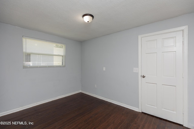 unfurnished room featuring dark wood-type flooring and a textured ceiling