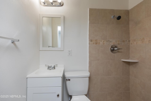 bathroom with vanity, a tile shower, and toilet