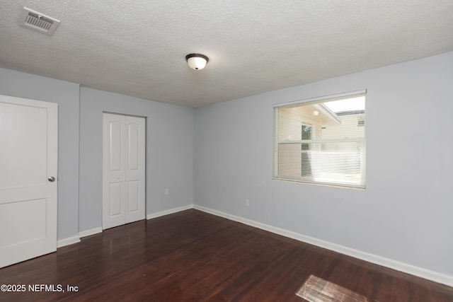 unfurnished bedroom featuring dark hardwood / wood-style flooring, a closet, and a textured ceiling