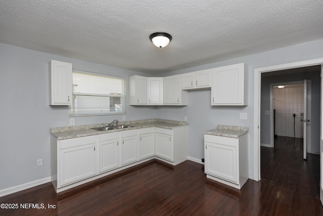 kitchen featuring dark hardwood / wood-style flooring, sink, a textured ceiling, and white cabinets